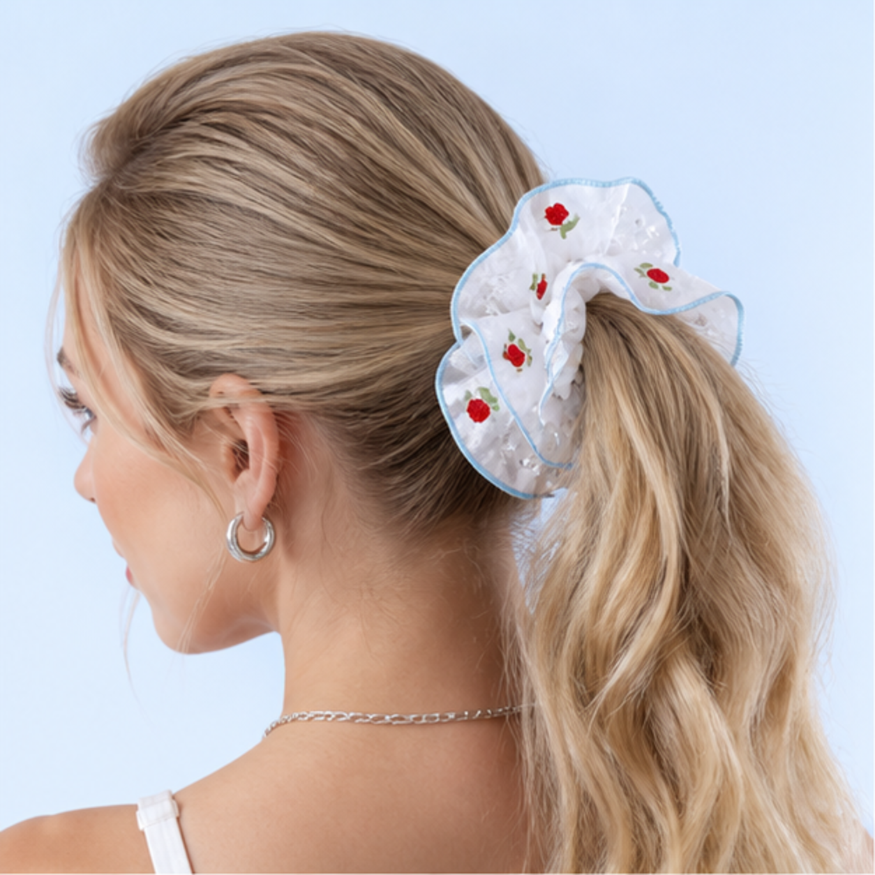 AI model wearing a LUSTREPOP floral scrunchie on a pale blue background