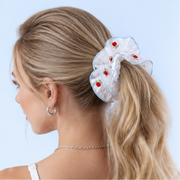 Adult model wearing the Rose Embroidery Pearl Scrunchie against a pale blue background