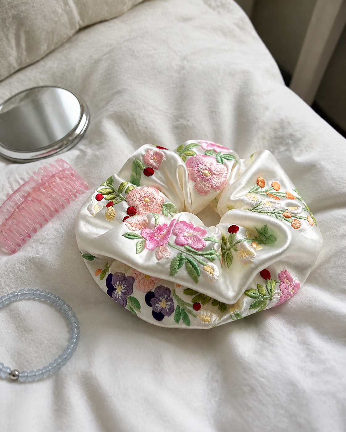 Embroidered Floral Satin Scrunchie flat lay on a white duvet